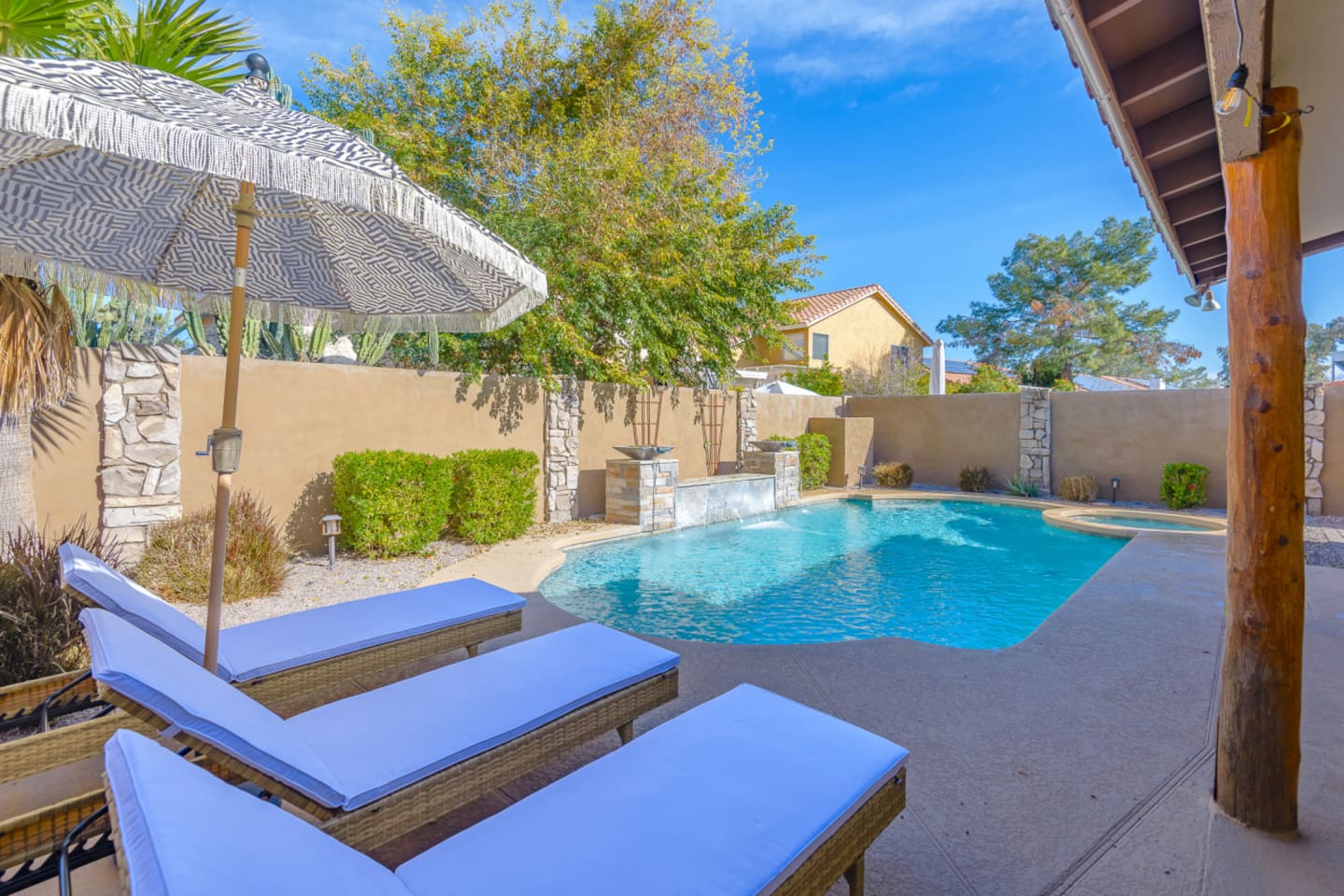 Poolside lounge area with seating, umbrella shade, and a tiki-style bar for sunny outdoor downtime.