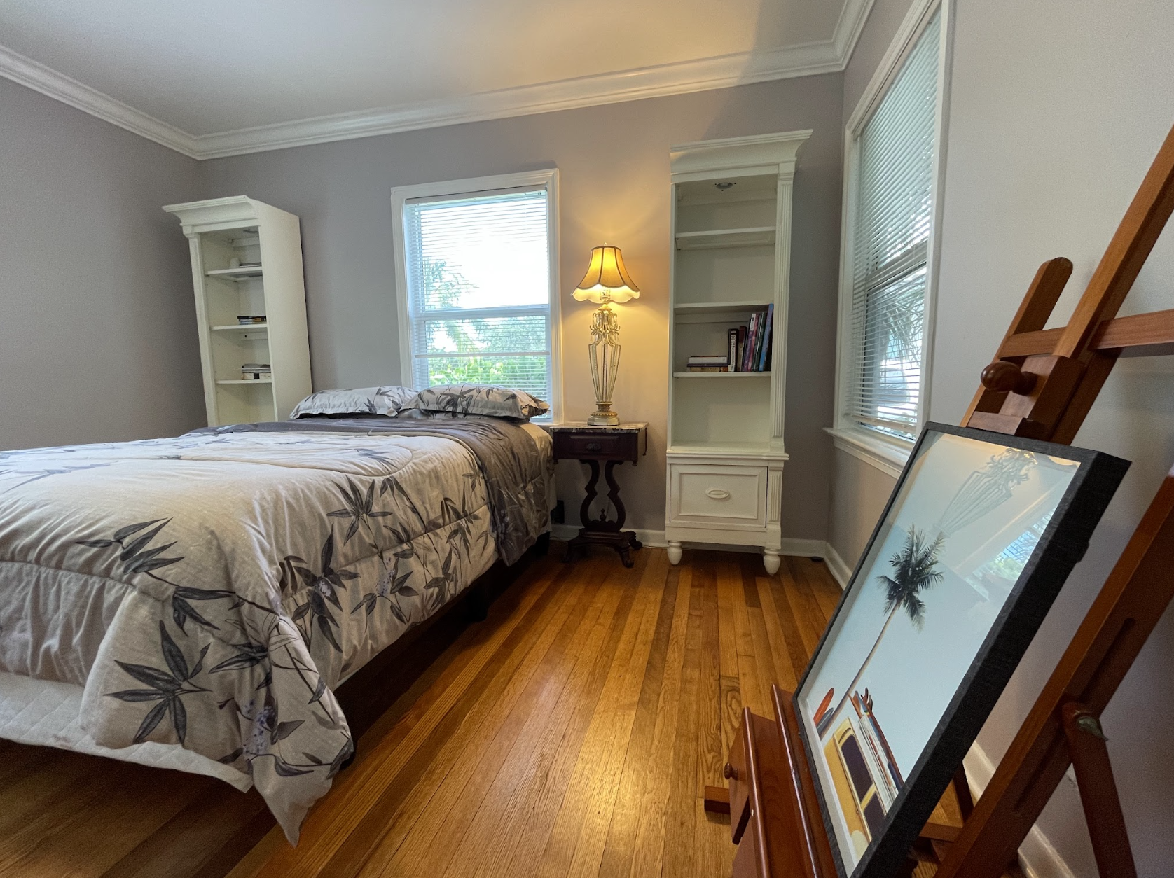 The second bedroom features a queen-zied bed and a stylish painter's floor stand.