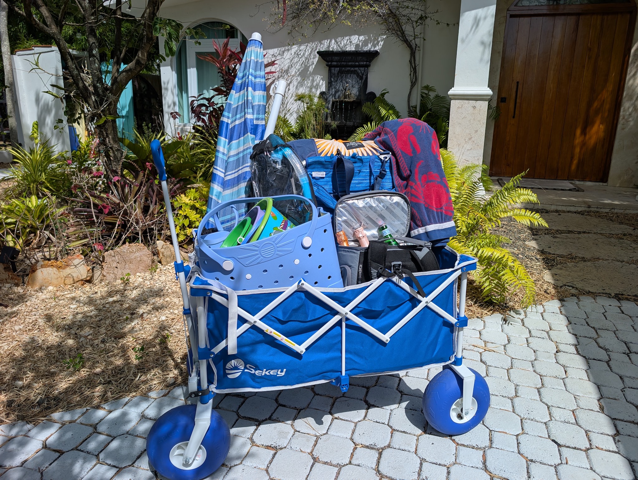 Blue beach wagon packed with complimentary gear including a beach umbrella, chairs, cooler, towels, and kids' sand toys provided for guests staying at Villa Coral in Dorado, Puerto Rico.