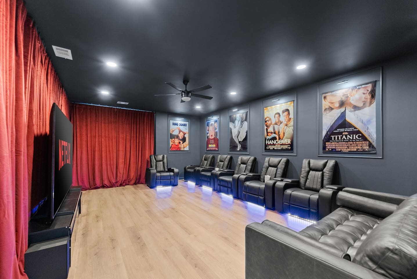Private home theater with a large screen, plush seating, and dramatic red curtains—perfect for an immersive movie experience.