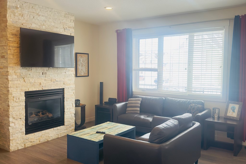 Cozy living room with stone fireplace, smart TV, and plush seating.