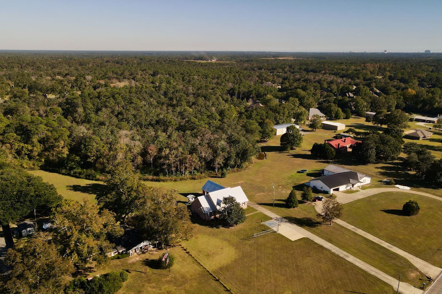 An aerial view reveals a peaceful neighborhood nestled against a backdrop of dense forest.