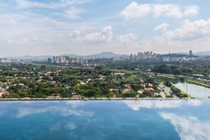 ✨ Vista incrível refletida na piscina infinita, uma experiência única no River One.