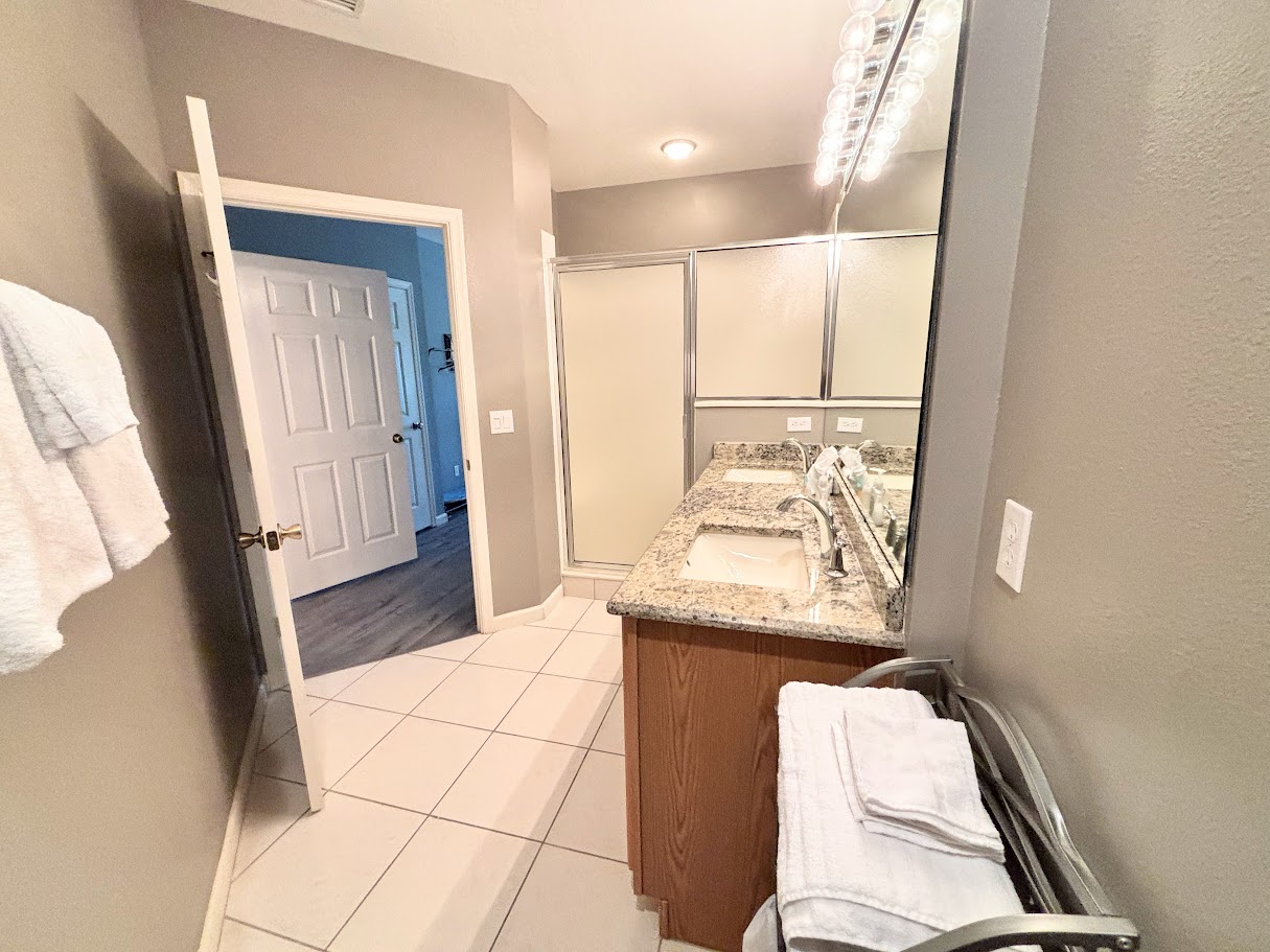 Bright bathroom with large vanity, tile flooring, and a shower enclosure.