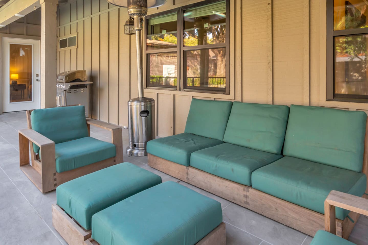 Outdoor sitting area with comfortable furniture, a gas BBQ grill, and propane heaters, creating a cozy and inviting space for relaxing, dining, and enjoying the backyard year-round.