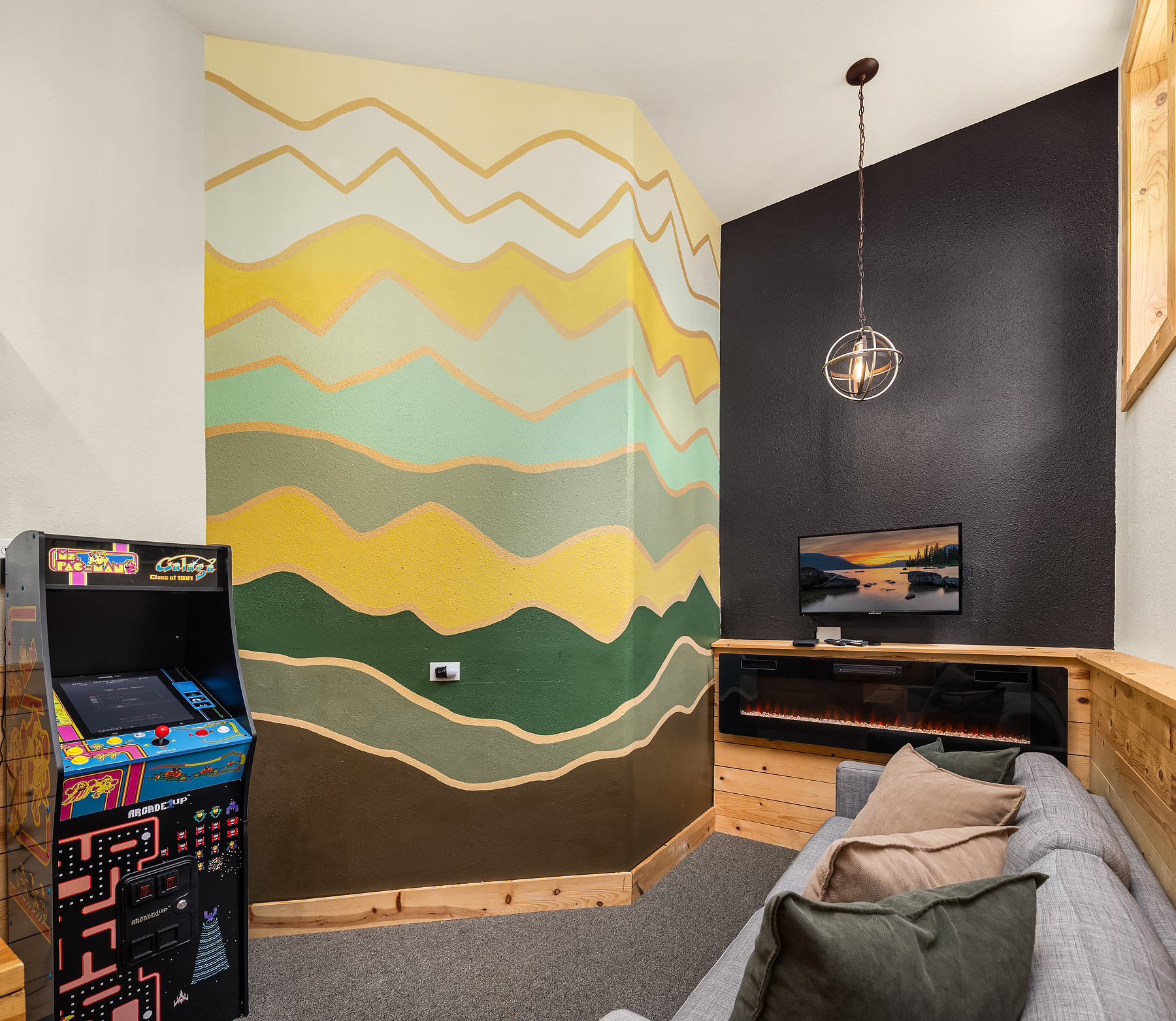 Basement sitting area with arcade game, electric fireplace and TV