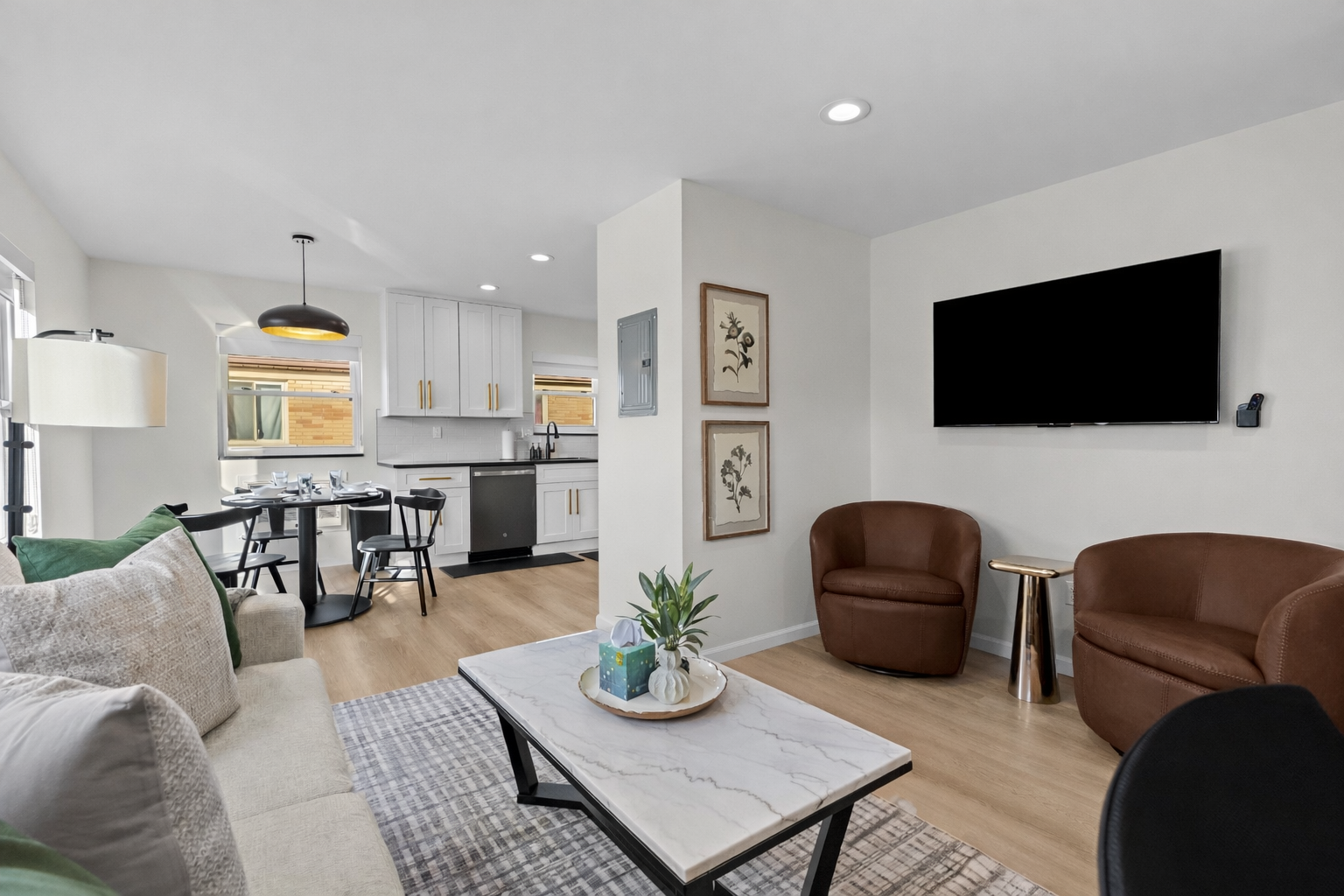 Modern open living space with cozy seating, smart TV, and seamless flow to kitchen and dining—bright, stylish, and perfect for relaxing or entertaining.
