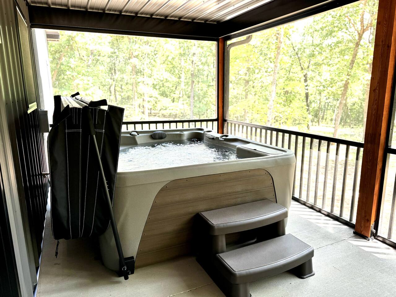 UNHOOK all four hot tub lid clasps and fold the cover OVER the metal bar. Lift the metal bar to suspend the hot tub lid conveniently in place. We are happy to go over the hot tub functions in person with you when you check-in.