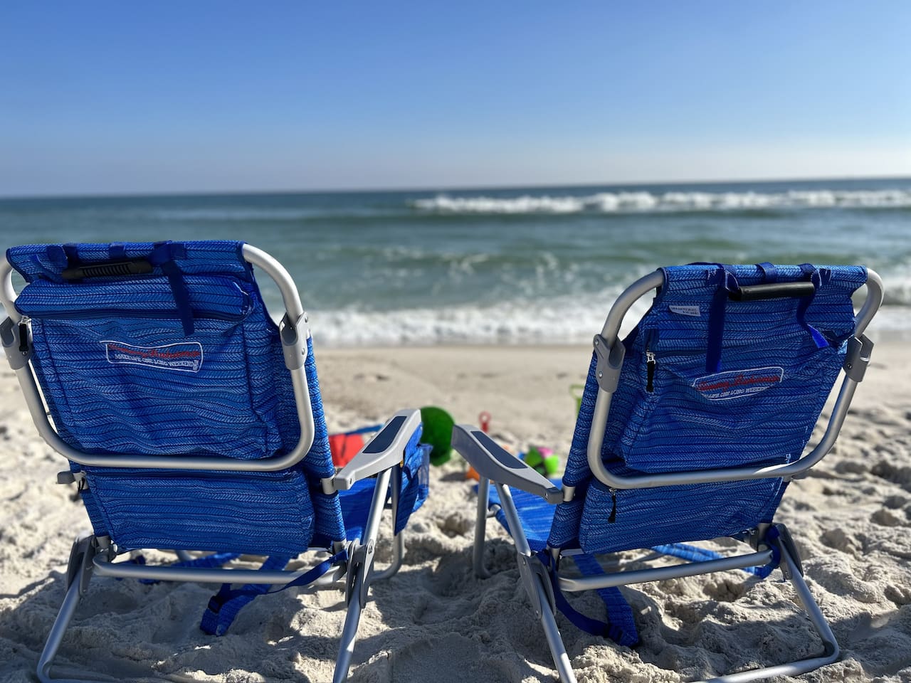 Serene beach day with blue chairs, golden sands, and tranquil ocean waves.