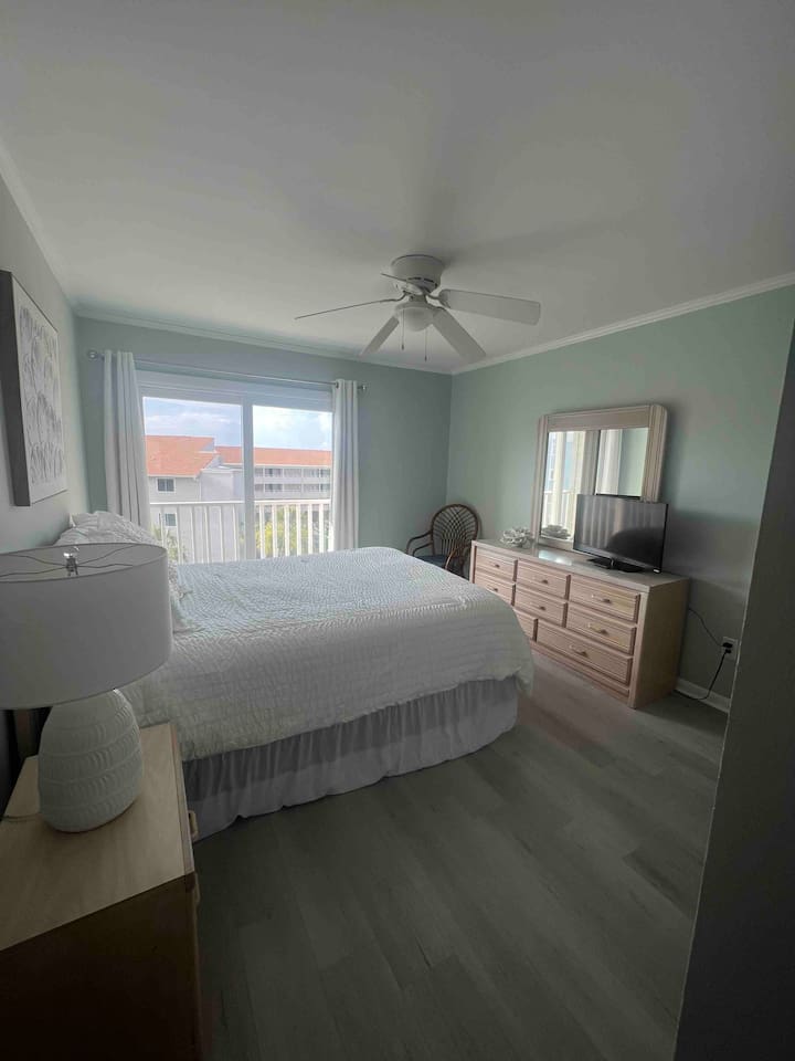 Relax in this airy Myrtle Beach master bedroom featuring soft coastal tones and a private balcony view.