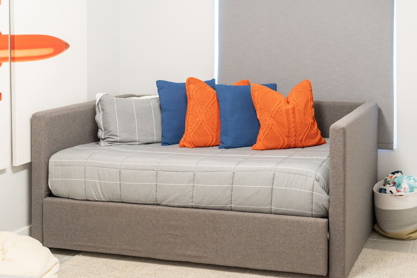  A comfy trundle bed with vibrant blue and orange pillows offers flexible sleeping space for guests or little ones.