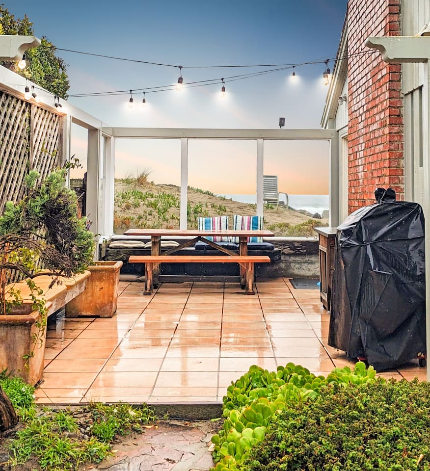 - Outdoor patio with picnic table, string lights, and views of the dunes  
- Features BBQ grill for easy outdoor cooking and dining experiences  
- Enclosed design offers a cozy gathering space in all seasons