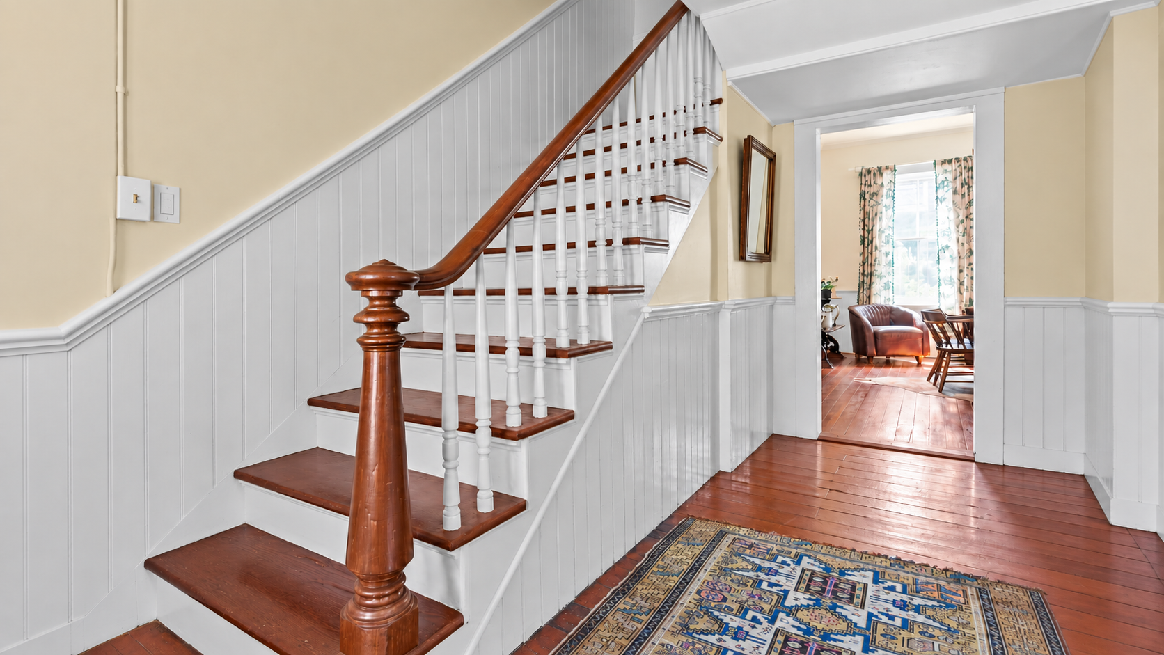 A glimpse of how Heritage House flows: the historic staircase rises from the central hall to 2 bedrooms and bath, the living room is at right and dining room and kitchen, beyond.  