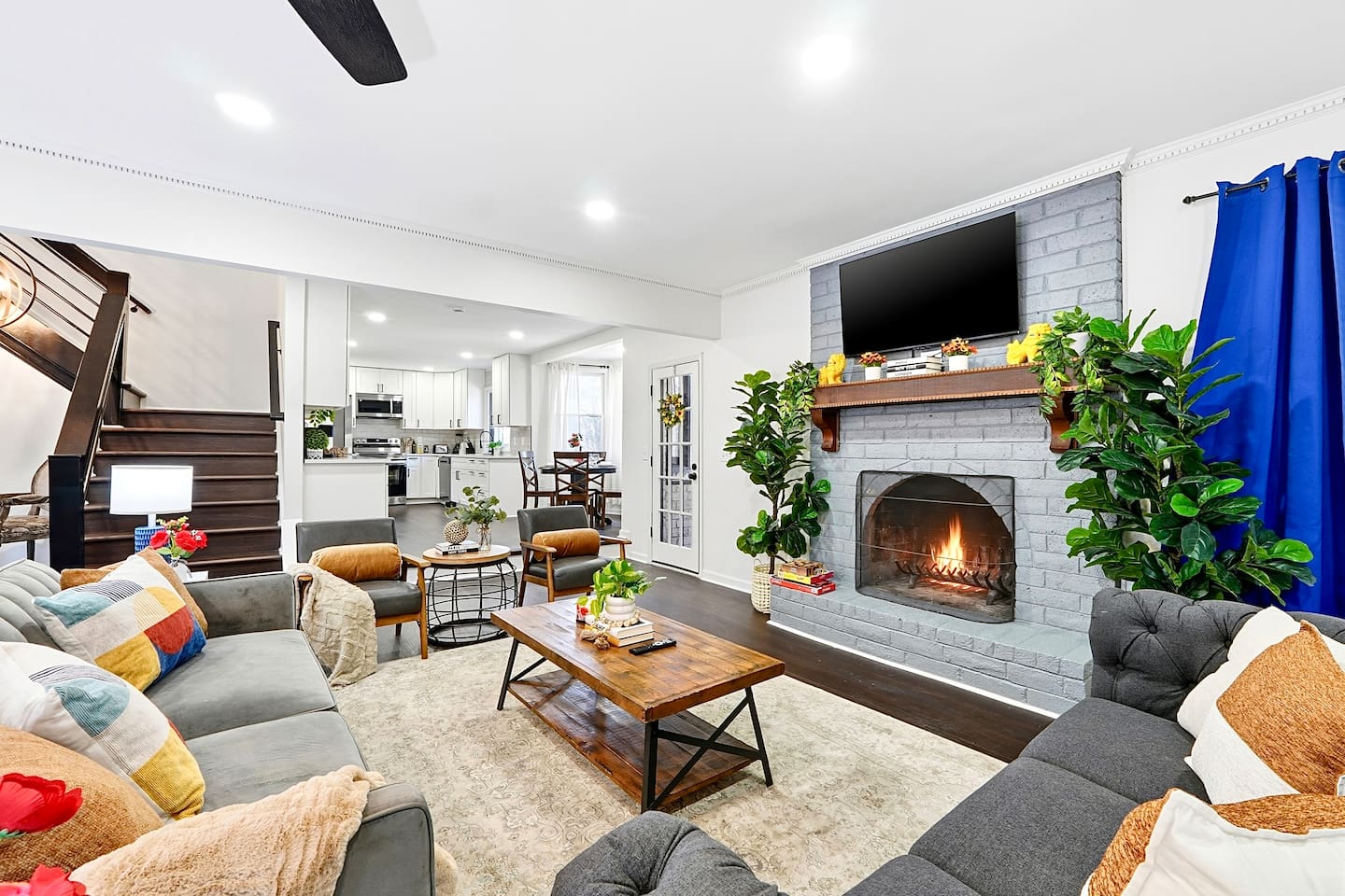 Warm and welcoming living room with two comfortable couches, two chairs, indoor plants, a cozy fireplace, and a TV powered by Google TV. Conveniently located as you walk through the front door and straight ahead from the primary side entrance. 