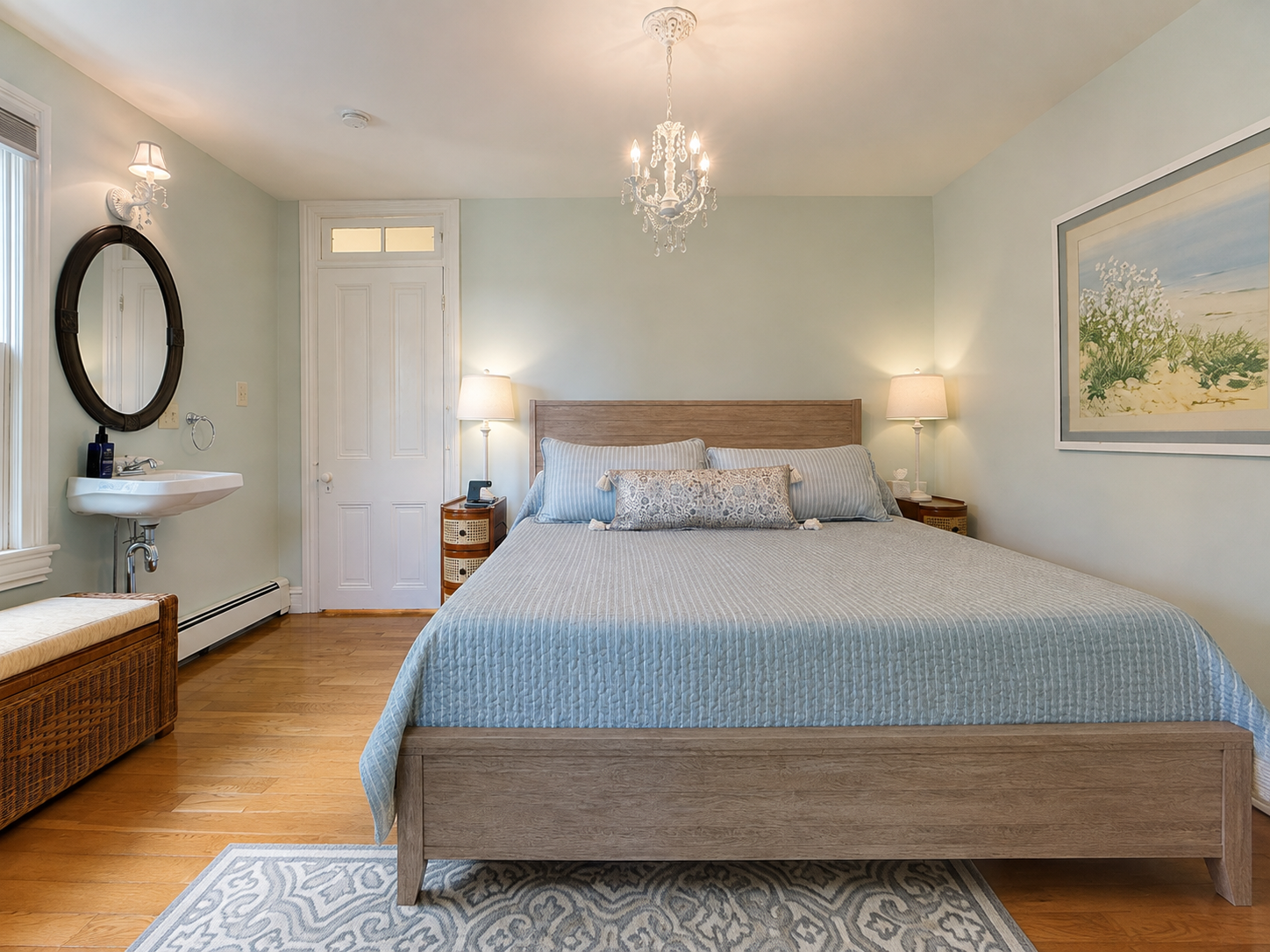 The second king bedroom on the second floor — a crystal chandelier, hardwood floors, and a palette that feels exactly right for a Cape May summer.