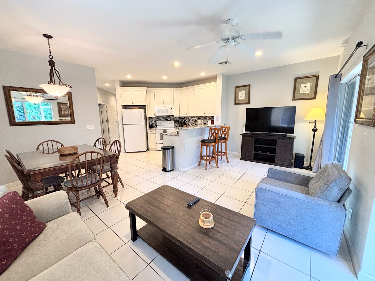 Bright open-concept living, dining, and kitchen area with tile flooring, comfortable seating, and a fully equipped kitchen.
