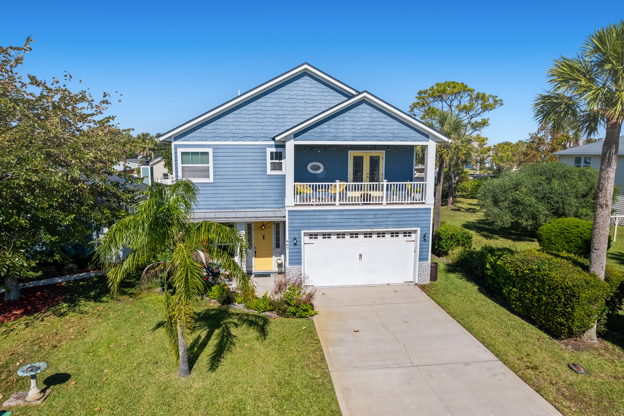 Charming coastal home with inviting balcony and tropical landscaping.