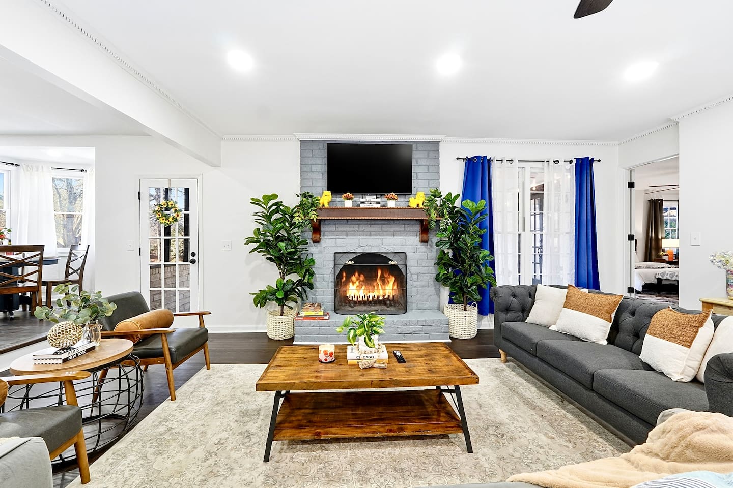 Warm and welcoming living room with two comfortable couches, two chairs, indoor plants, a cozy fireplace, and a TV powered by Google TV. Conveniently located as you walk through the front door and straight ahead from the primary side entrance. 