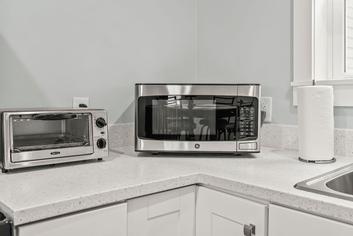 Convenient countertop setup with microwave, toaster oven, and paper towels — perfect for quick meals or reheating.