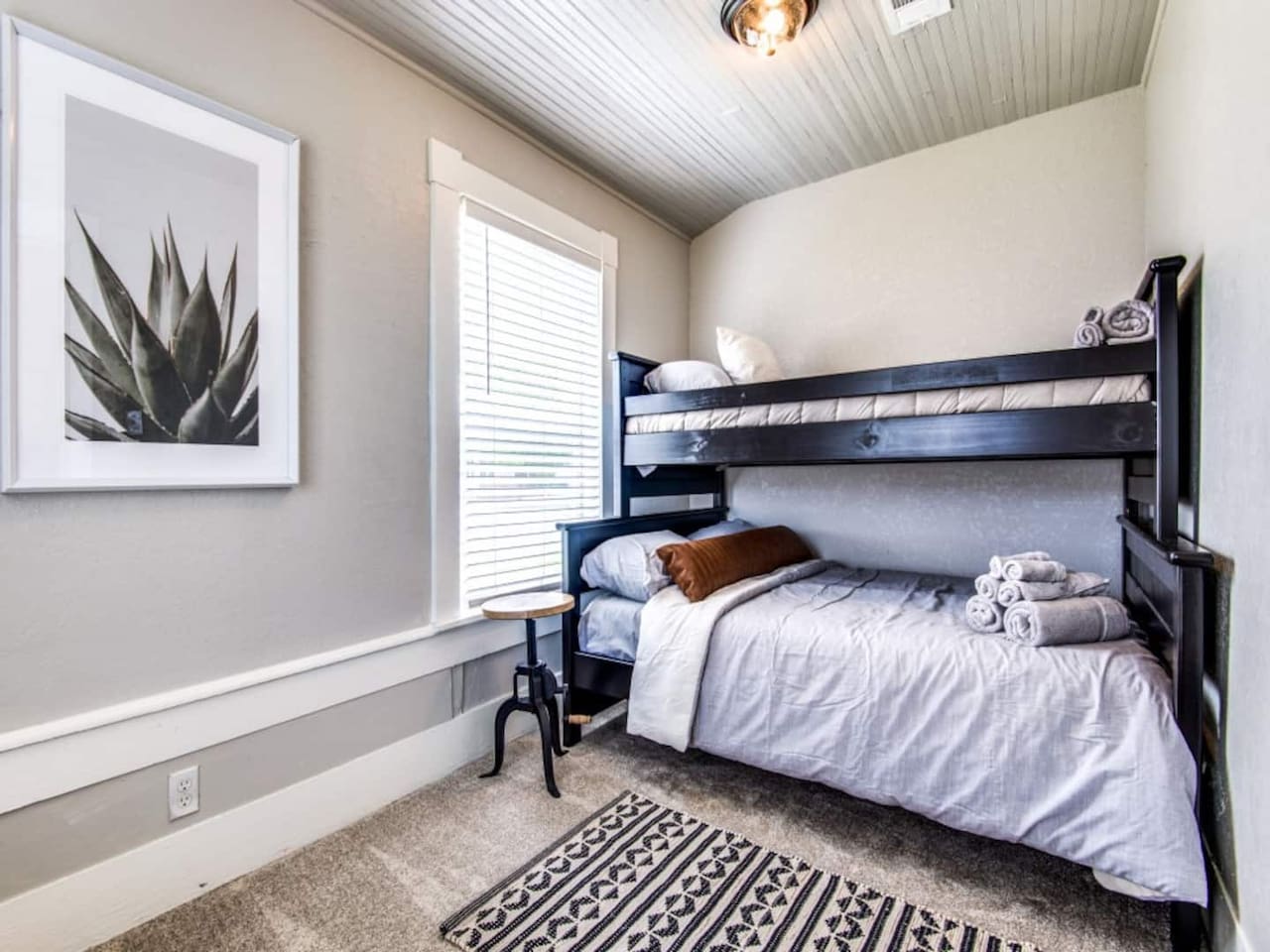 Twin-over-full bunk bedroom with shiplap ceiling, natural light, and hardwood floors. Sleeps 3 in this modern farmhouse Airbnb in Aubrey TX. Pack and Play available on request. Total capacity 7 guests near downtown Aubrey dining.