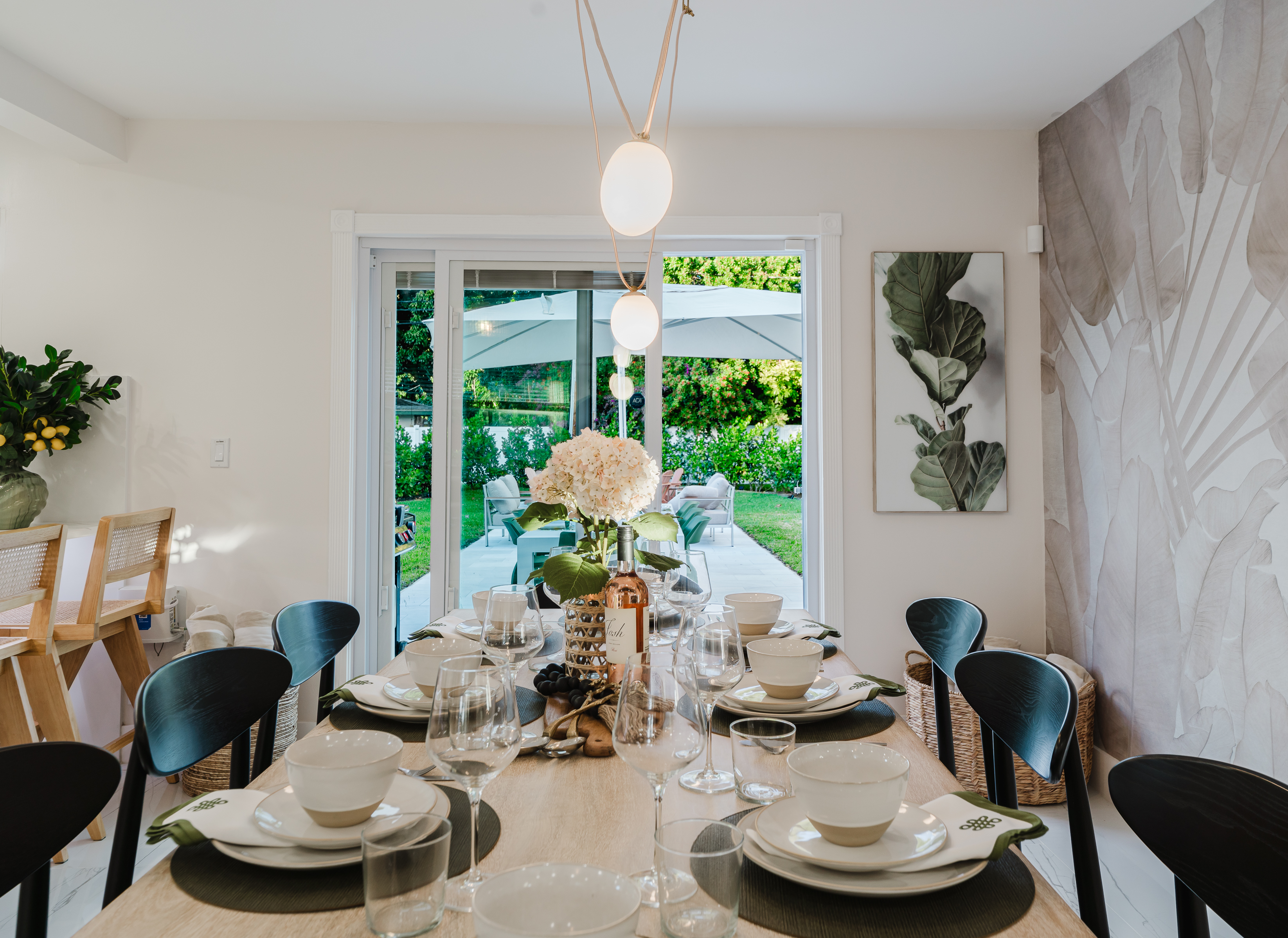 Designer dining room featuring a Gwyneth Paltrow GOOP statement light, custom wallpaper, and seating for 12. Backlit counter seating and seamless access to the patio and backyard make this space ideal for family meals and entertaining.