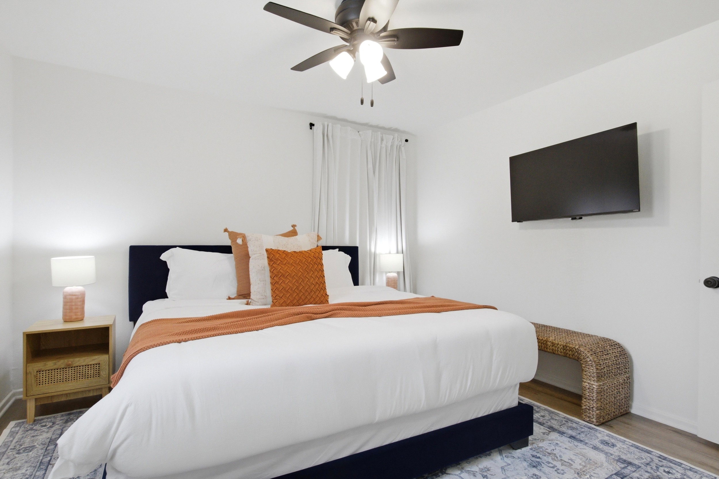 Bedroom 2 with King Bed, mounted 42 inch Smart TV, and Ceiling Fan. Streaming and bedside reading for late nights after Texas Live and AT&T Stadium events.
