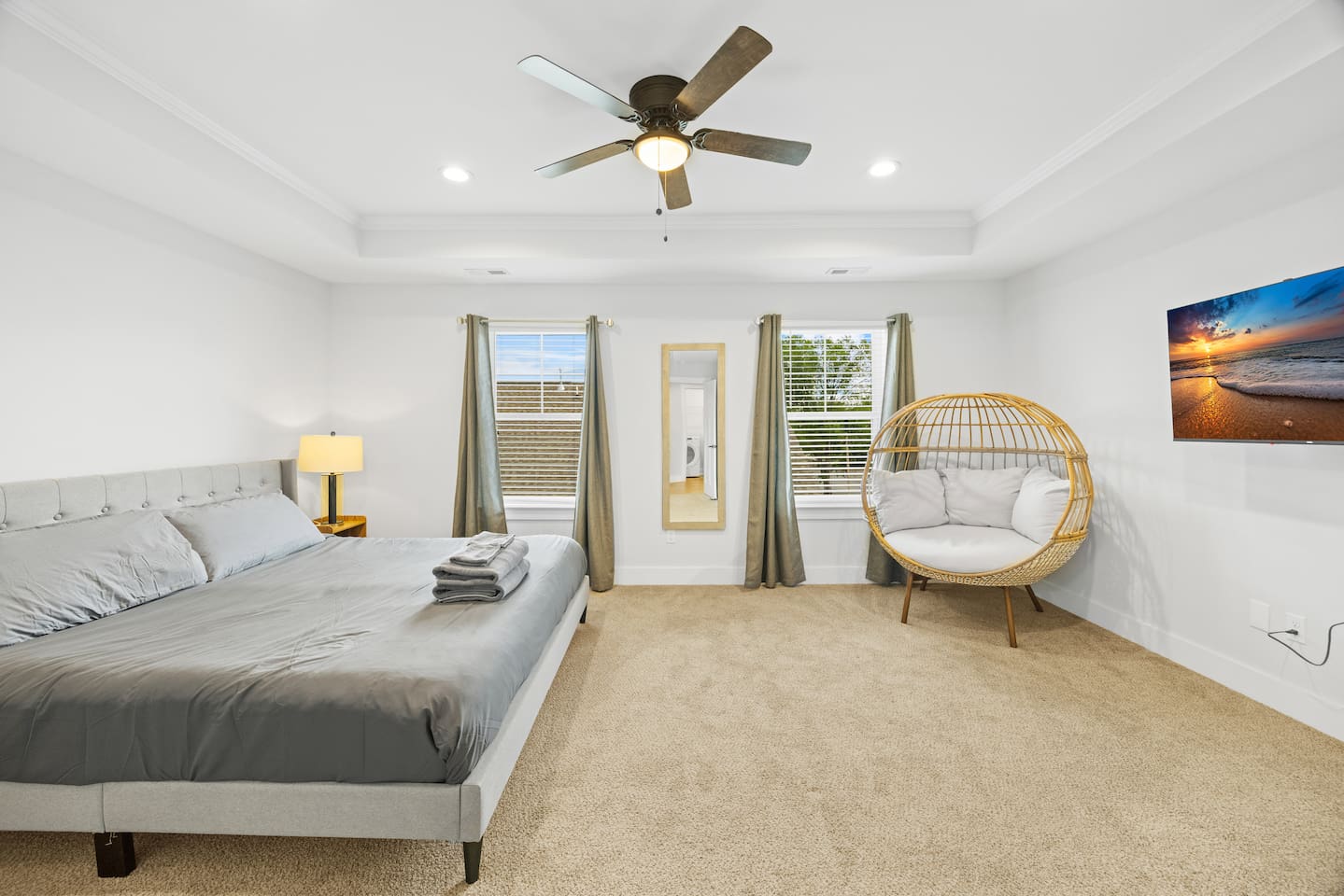 Unwind in this expansive master bedroom featuring a plush king-size bed, luxurious carpet, and modern lighting. Two large windows allow natural light to fill the room, while blackout curtains ensure a restful night’s sleep.