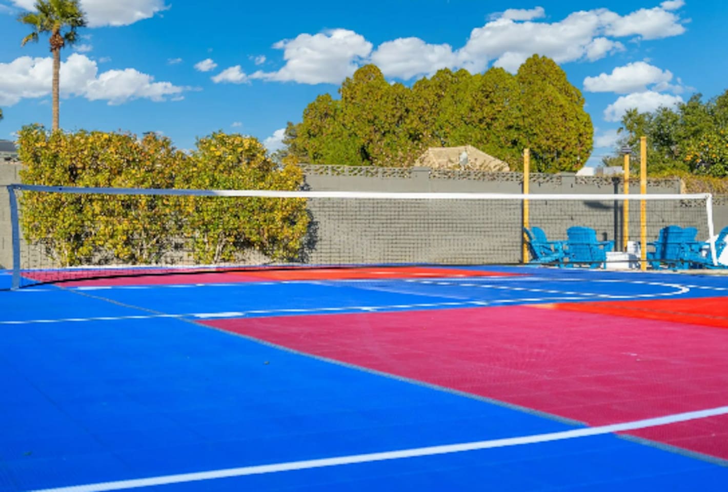 A full volleyball court adds even more room to play, framed by lush greenery and blue Adirondack chairs for anyone cheering from the sidelines.