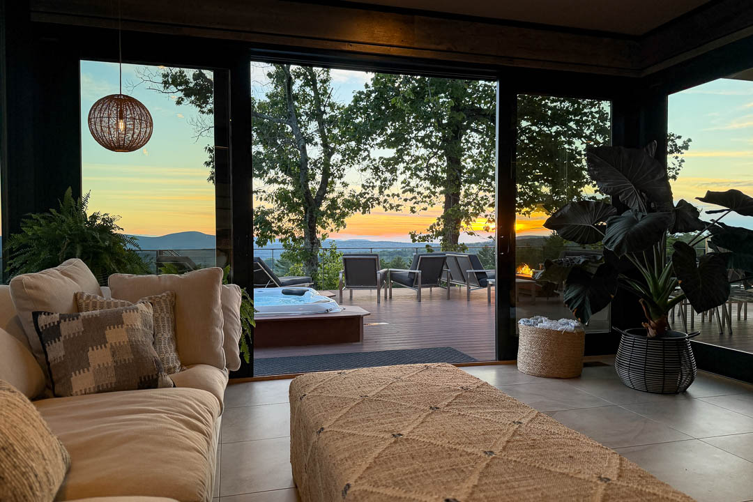 The sunroom at Sunset Falls looking out through open glass doors to the hot tub deck at sunset &mdash; Berkshires