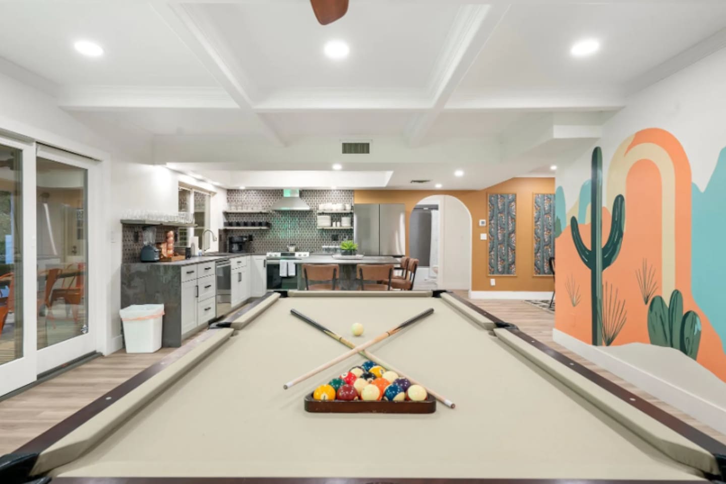 Rack 'em up on the full-size pool table, with the kitchen and a vibrant cactus mural just beyond, keeping everyone connected while the game's on.
