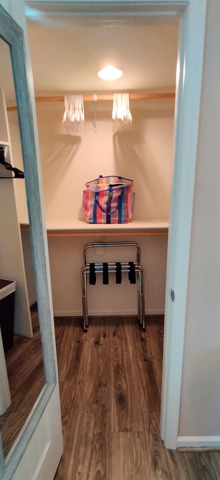 Spacious master closet with plenty of hangers, extra pillows, and two luggage racks.