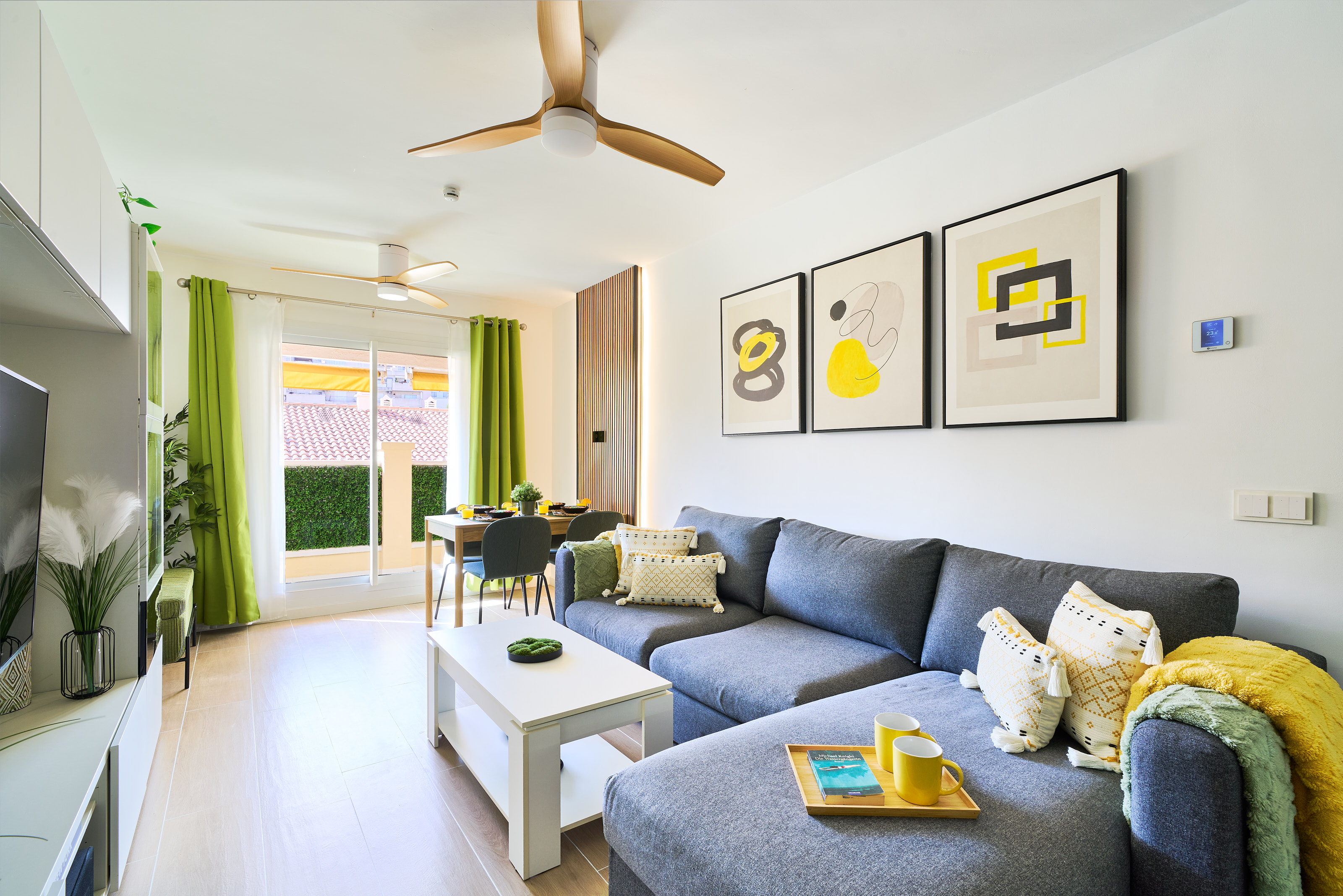 Stylish open-plan living room with a modern kitchen, smart TV, and natural light throughout — ideal for relaxing or sharing a glass of wine after a day by the beach.