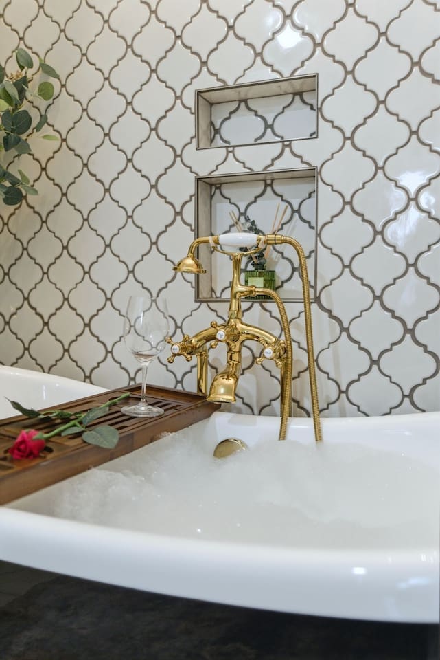 Luxurious soaking tub with elegant gold fixtures, perfect for unwinding with a glass of wine 
