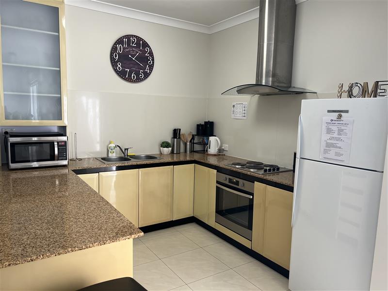 Galley kitchen with full size fridge, electric stove top & full under bench oven