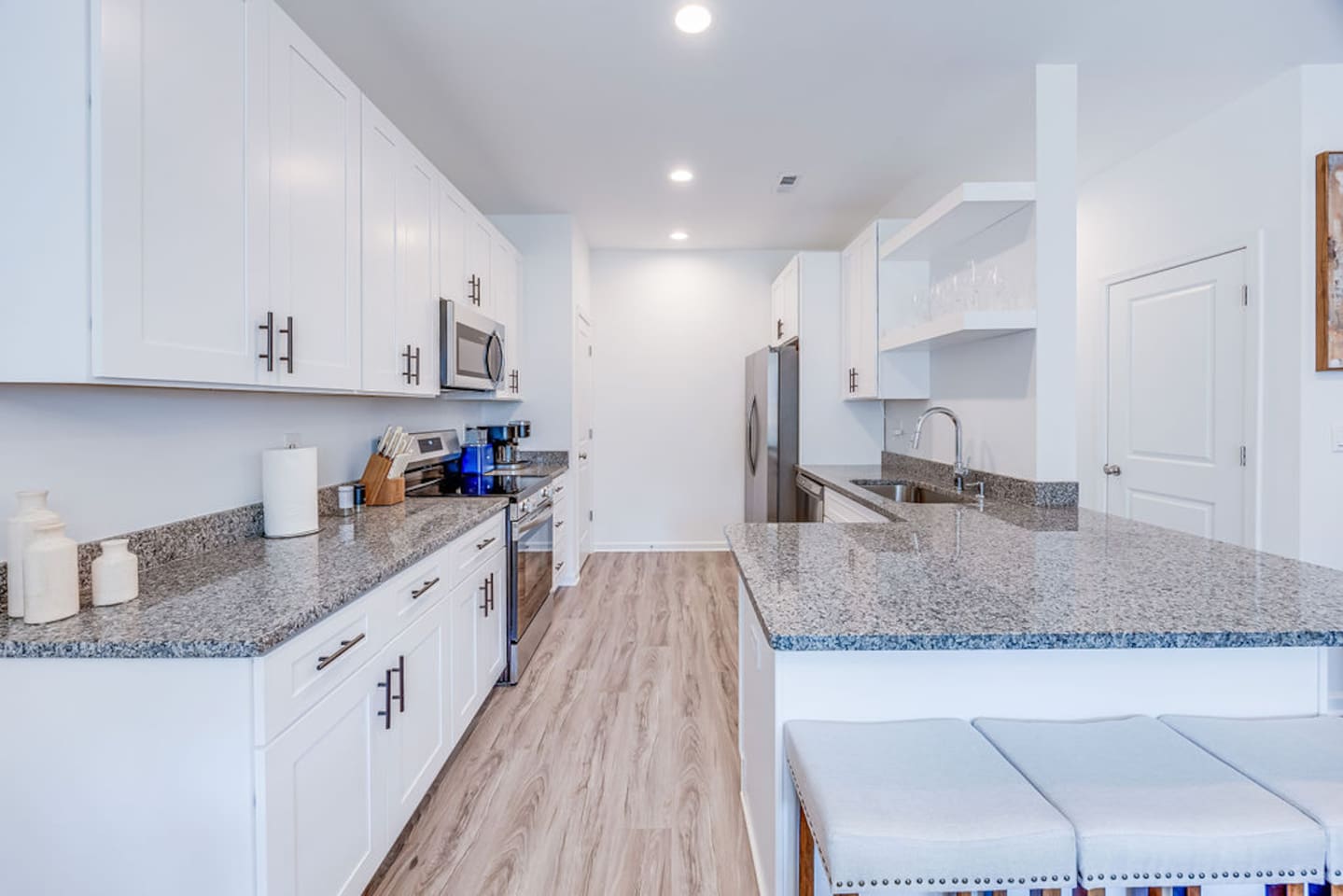 Bright and modern, the kitchen boasts white cabinets, dark countertops, and stylish open shelving for a sleek and functional design.