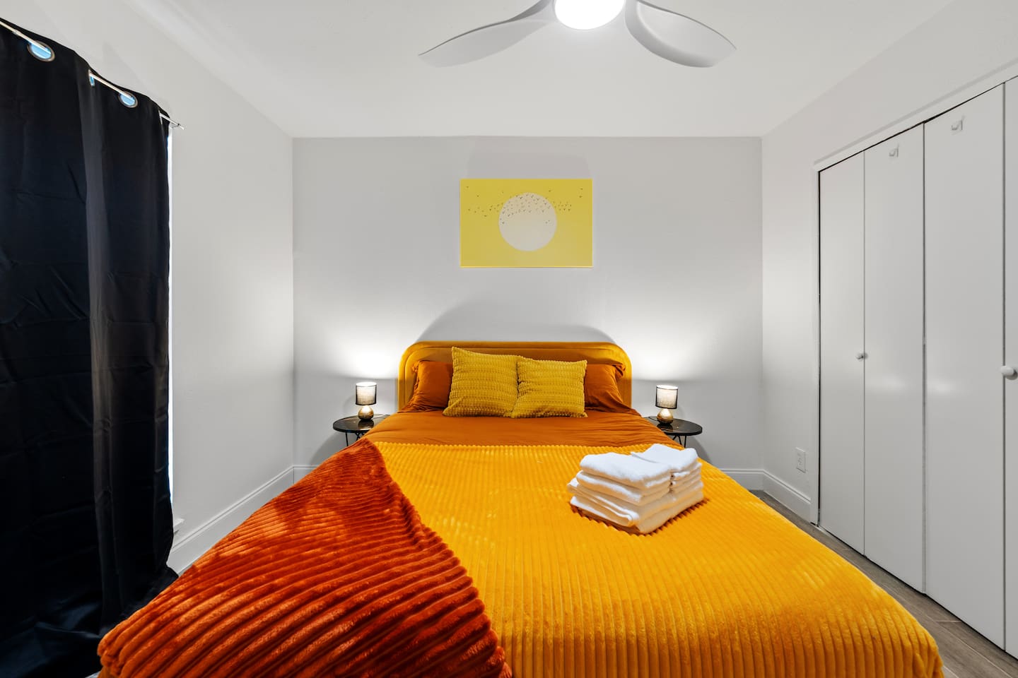 Bright bedroom with cozy orange bedding, blackout curtains, and ample closet space—perfect for restful nights and relaxed mornings.