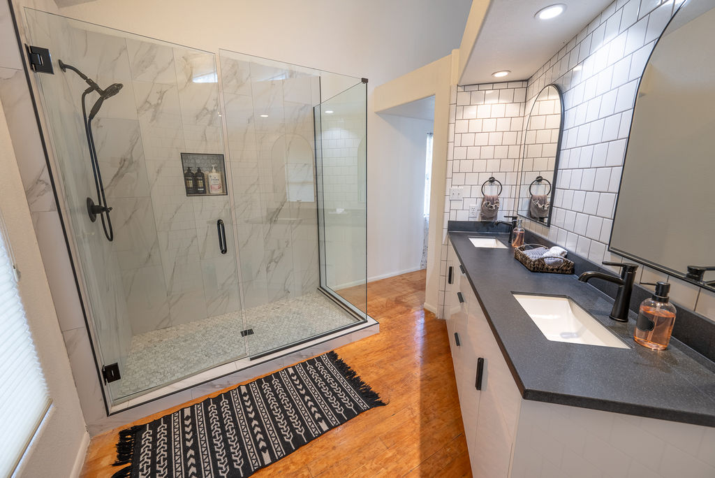 Newly remodeled master bathroom with a modern glass shower and double vanity.