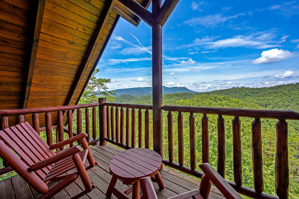 A wooden deck with chairs offers a scenic view of the majestic mountains