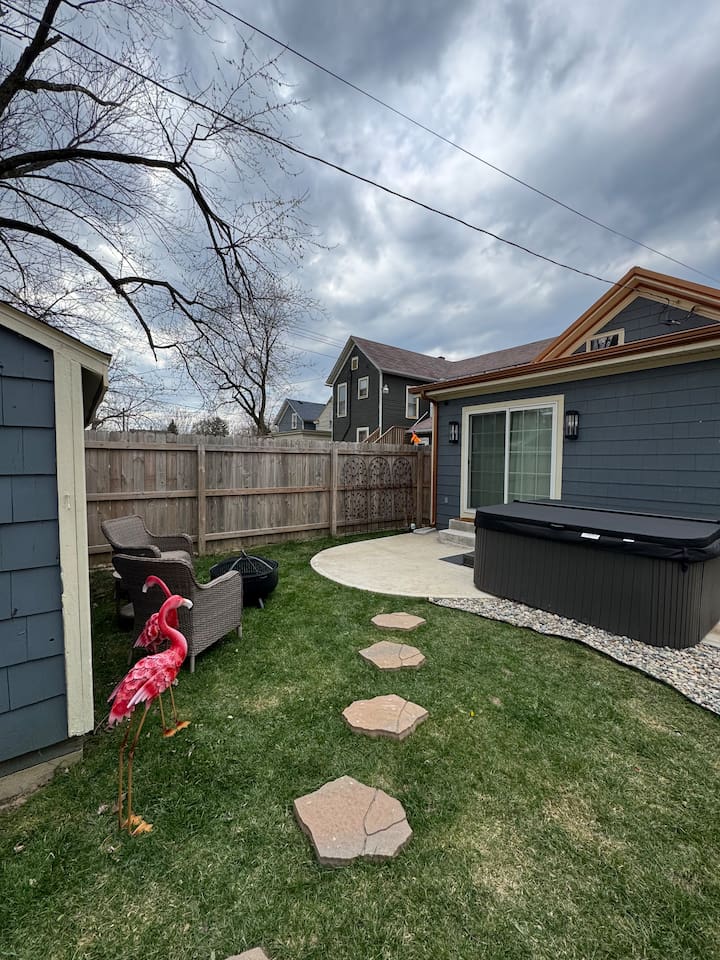 Private fenced backyard with a fire pit, lounge chairs, and charming stepping-stone path—ideal for gathering, unwinding, and enjoying outdoor living.