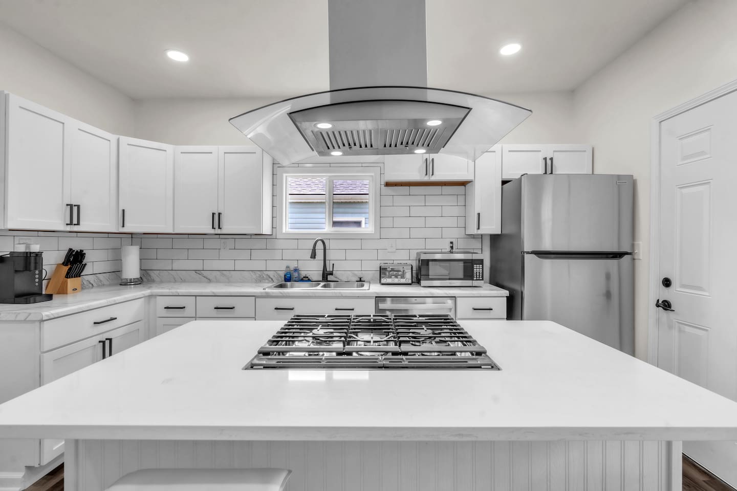 Enjoy the convenience of a center island with a burner, a modern sink, and a spacious fridge, all set in an elegantly designed kitchen for a functional and stylish cooking experience.