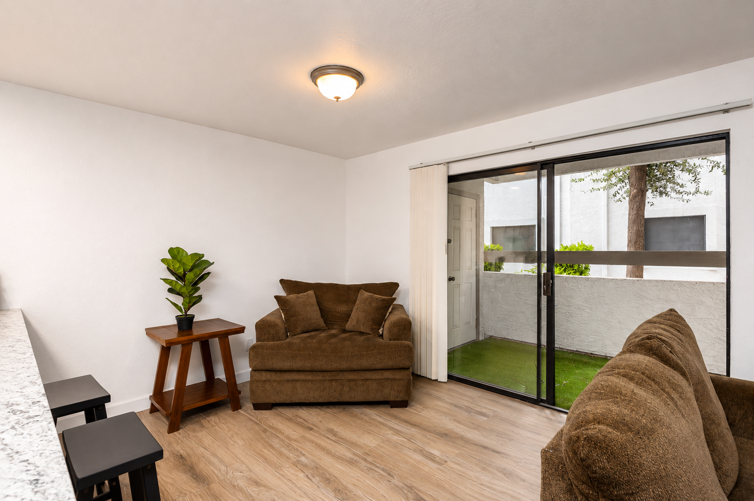Seating area with an oversized chair, side table, bench seating, and sliding door access to the small private patio.
