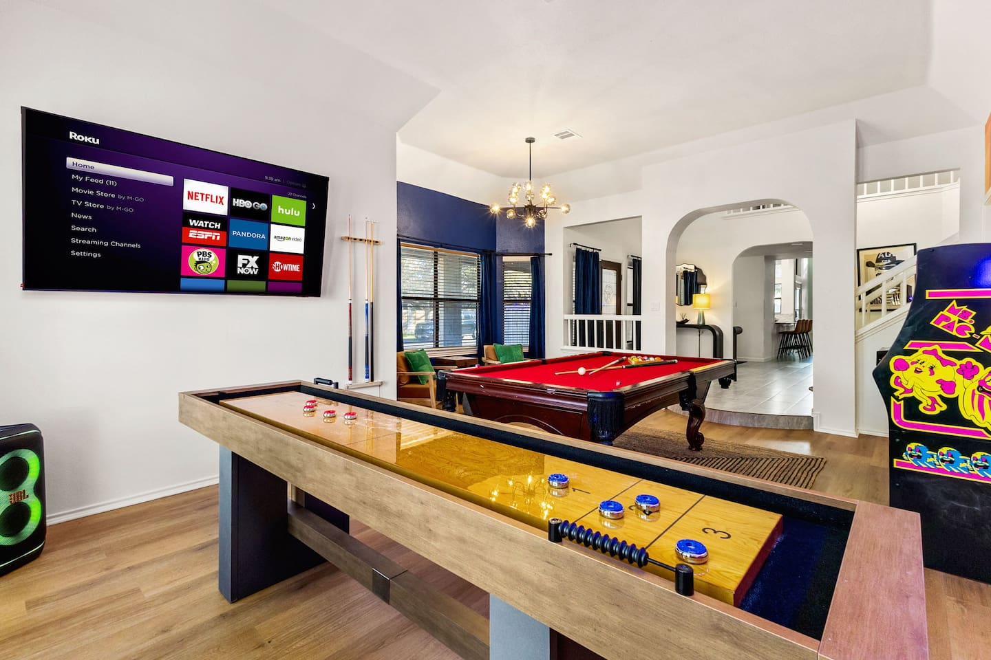 This fun-filled game zone features a shuffleboard table, pool table, smart TV with streaming apps, vintage arcade game, and sleek decor—perfect for hosting game nights or just kicking back in style with friends and family.