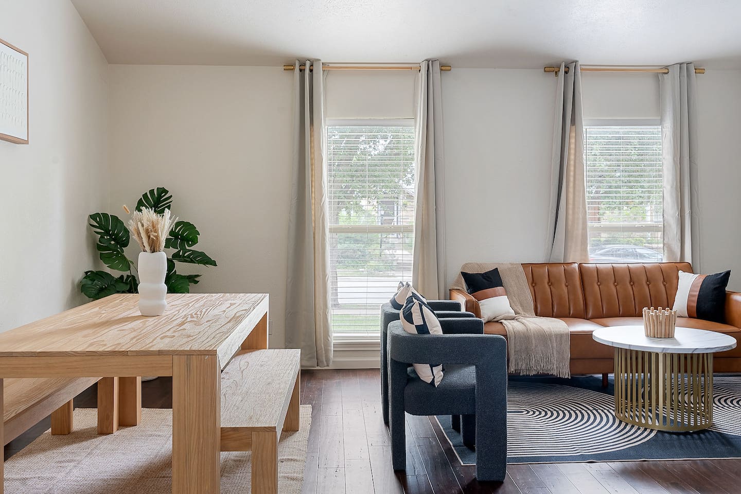 Feel at home in this inviting space featuring a rustic dining table and a plush seating area. Natural light floods through large windows.