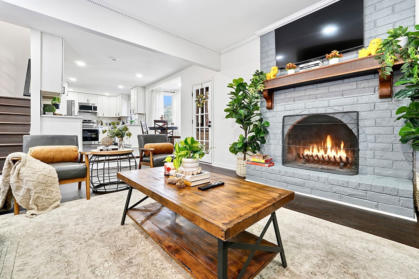 Warm and welcoming living room with two comfortable couches, two chairs, indoor plants, a cozy fireplace, and a TV powered by Google TV. Conveniently located as you walk through the front door and straight ahead from the primary side entrance. 