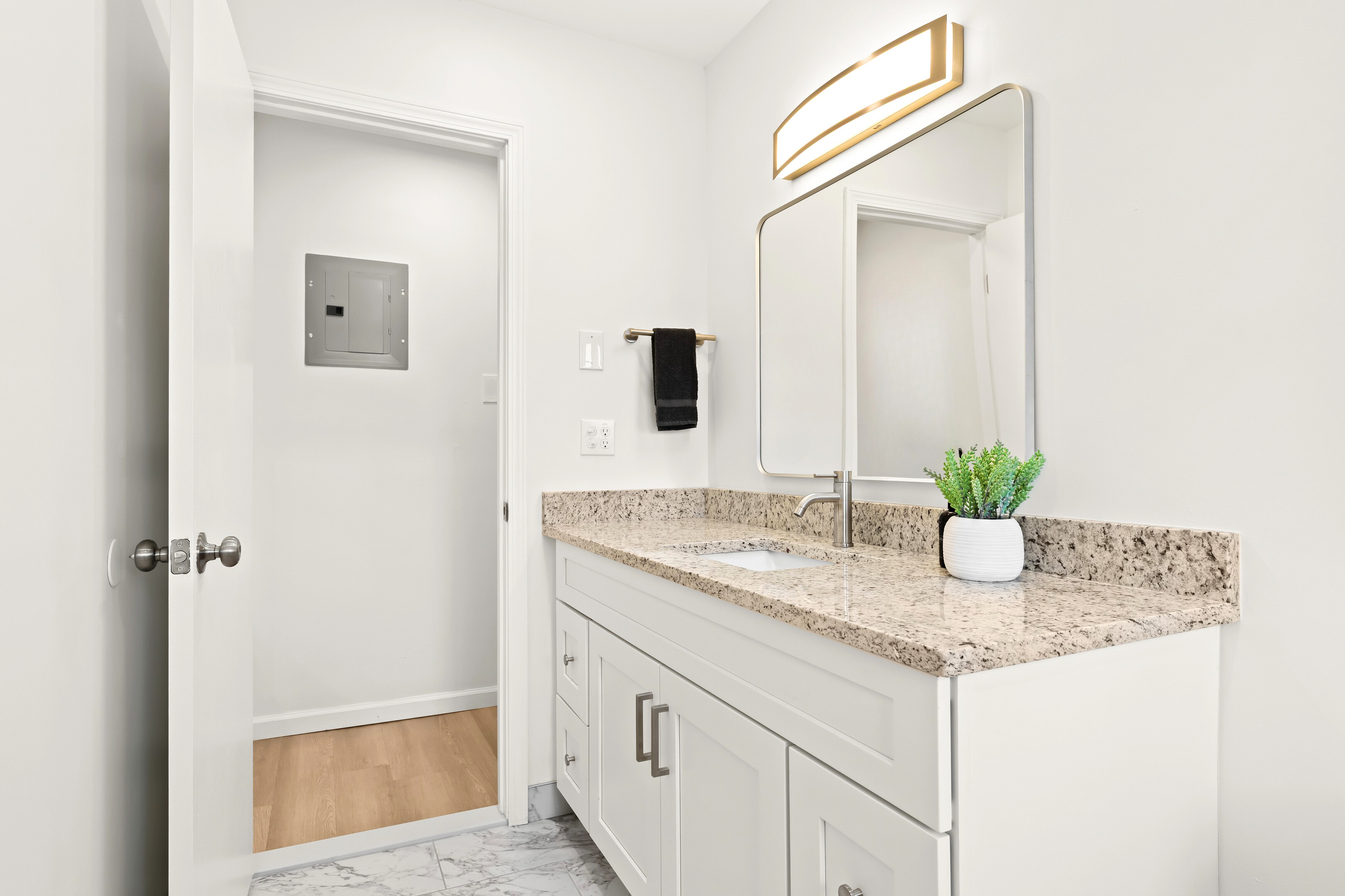 Bathroom vanity with granite countertop, well-lit mirror, and under-sink storage.