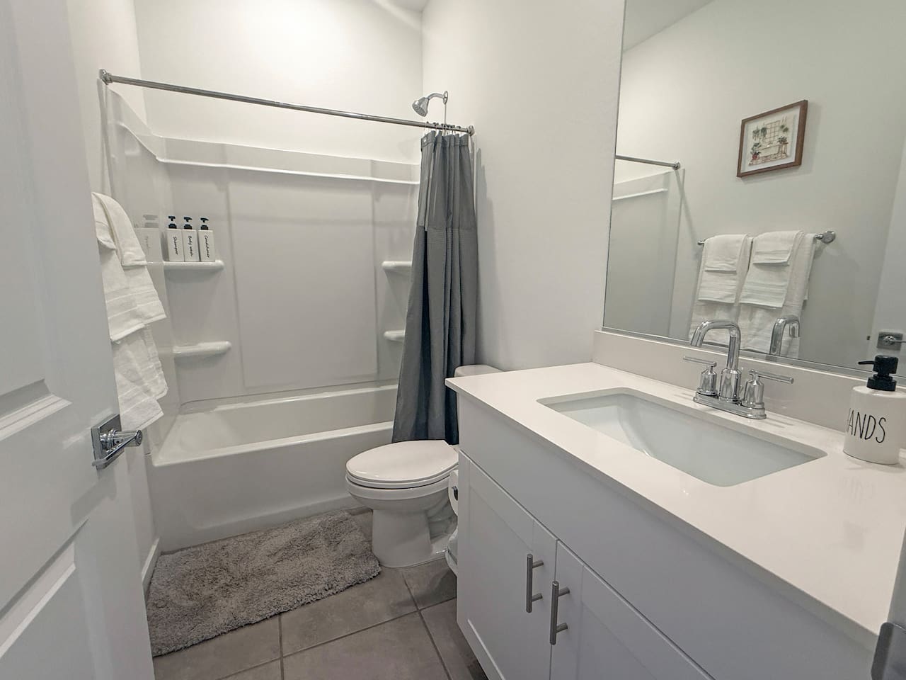 Bathroom with tub-shower, toilet, vanity, and towels