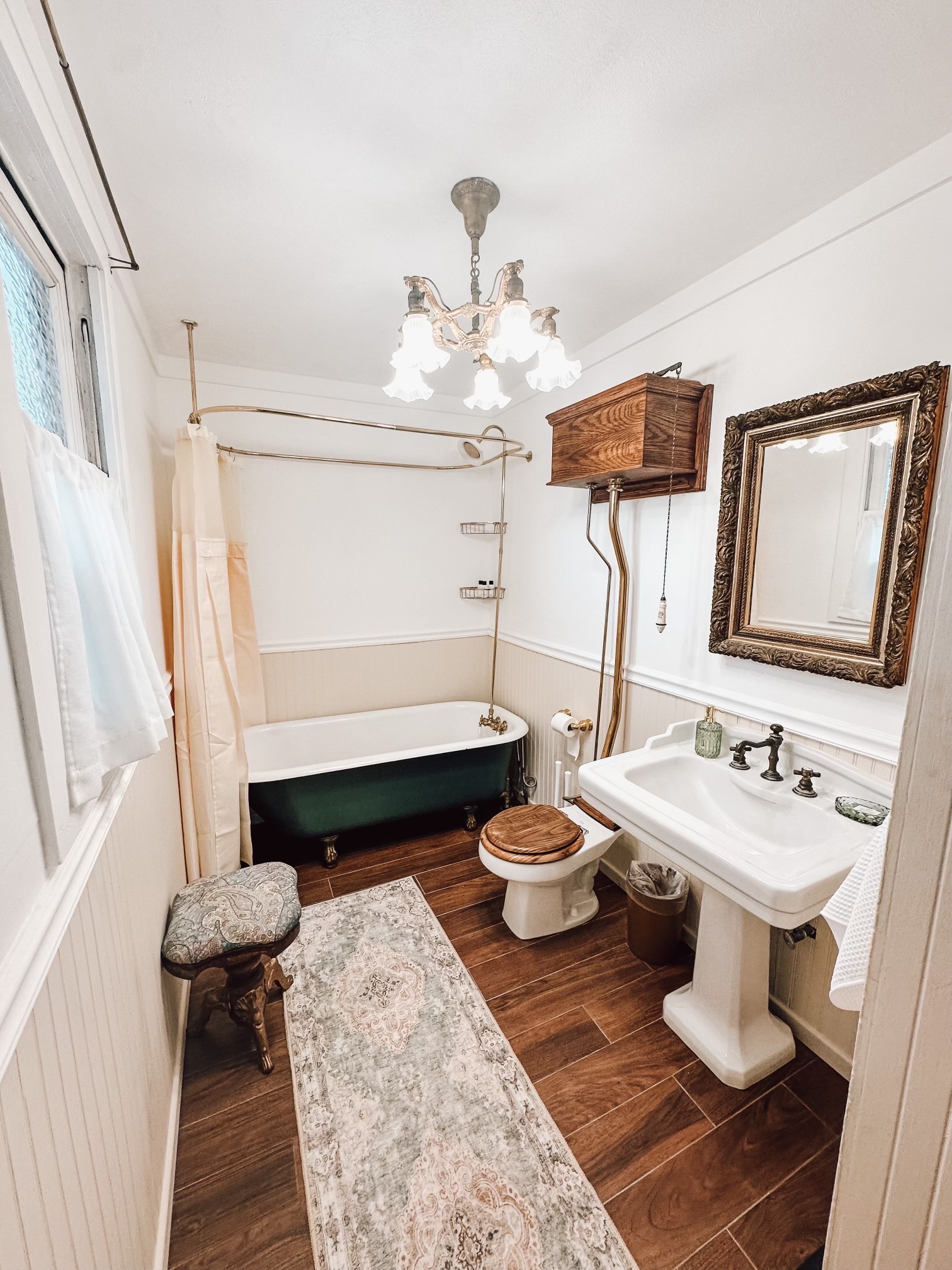 Slip into the deep clawfoot tub in the primary suite’s private bath, where a pedestal sink, pull chain commode and a stained glass window continue the home’s historic character. The dressing room creates a graceful buffer from the bedroom.