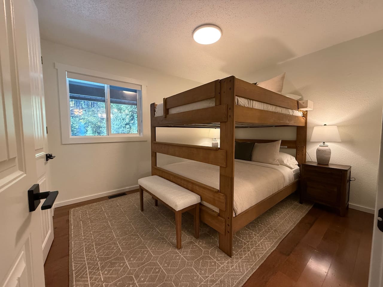 The main floor bedroom features a unique adult bunk bed with a queen-size mattress on both the top and bottom bunks, comfortably sleeping four adults. This layout is designed to maximize space without sacrificing comfort.