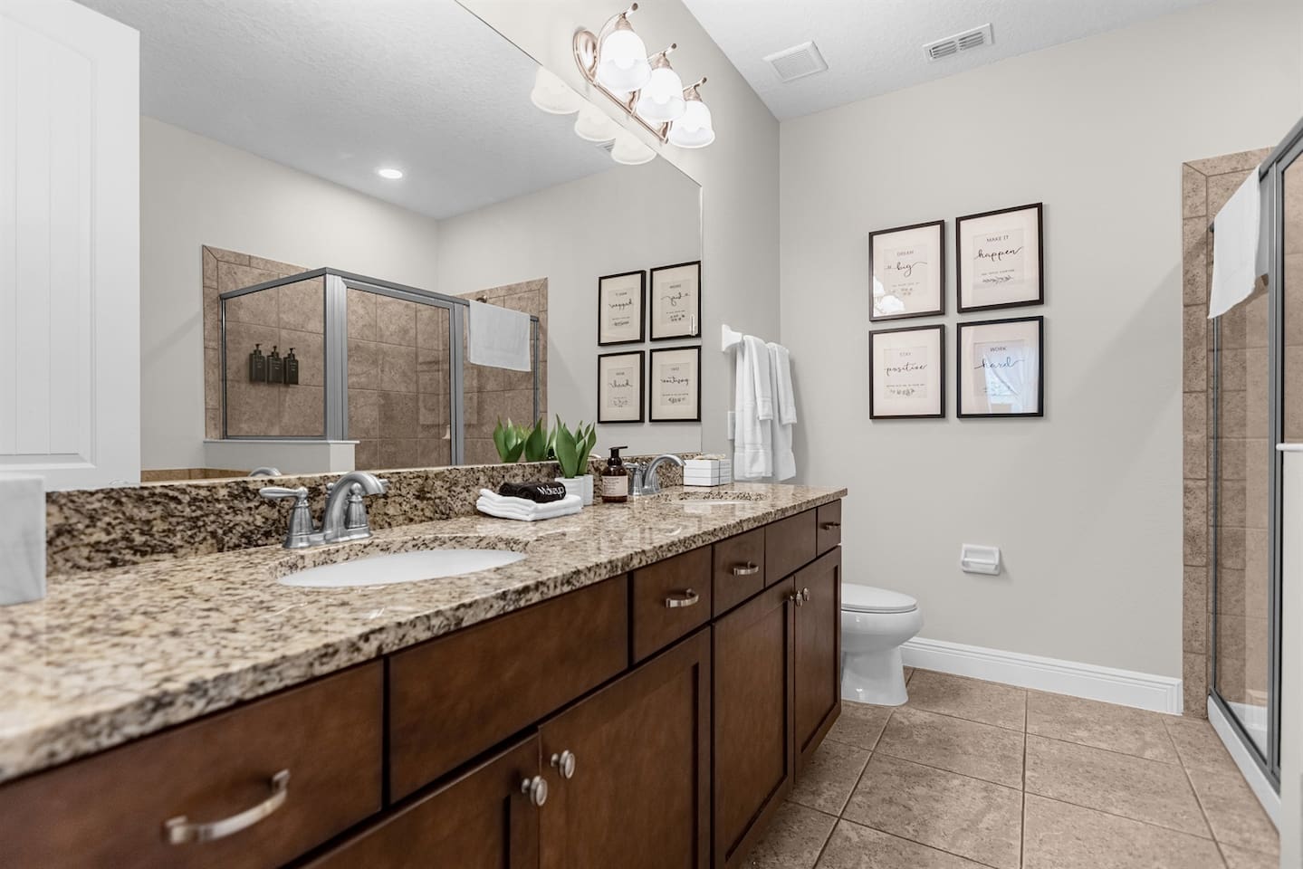Modern bathroom equipped with a generous vanity area, a toilet, and a walk-in shower, offering a stylish and functional space for relaxation and refreshment.