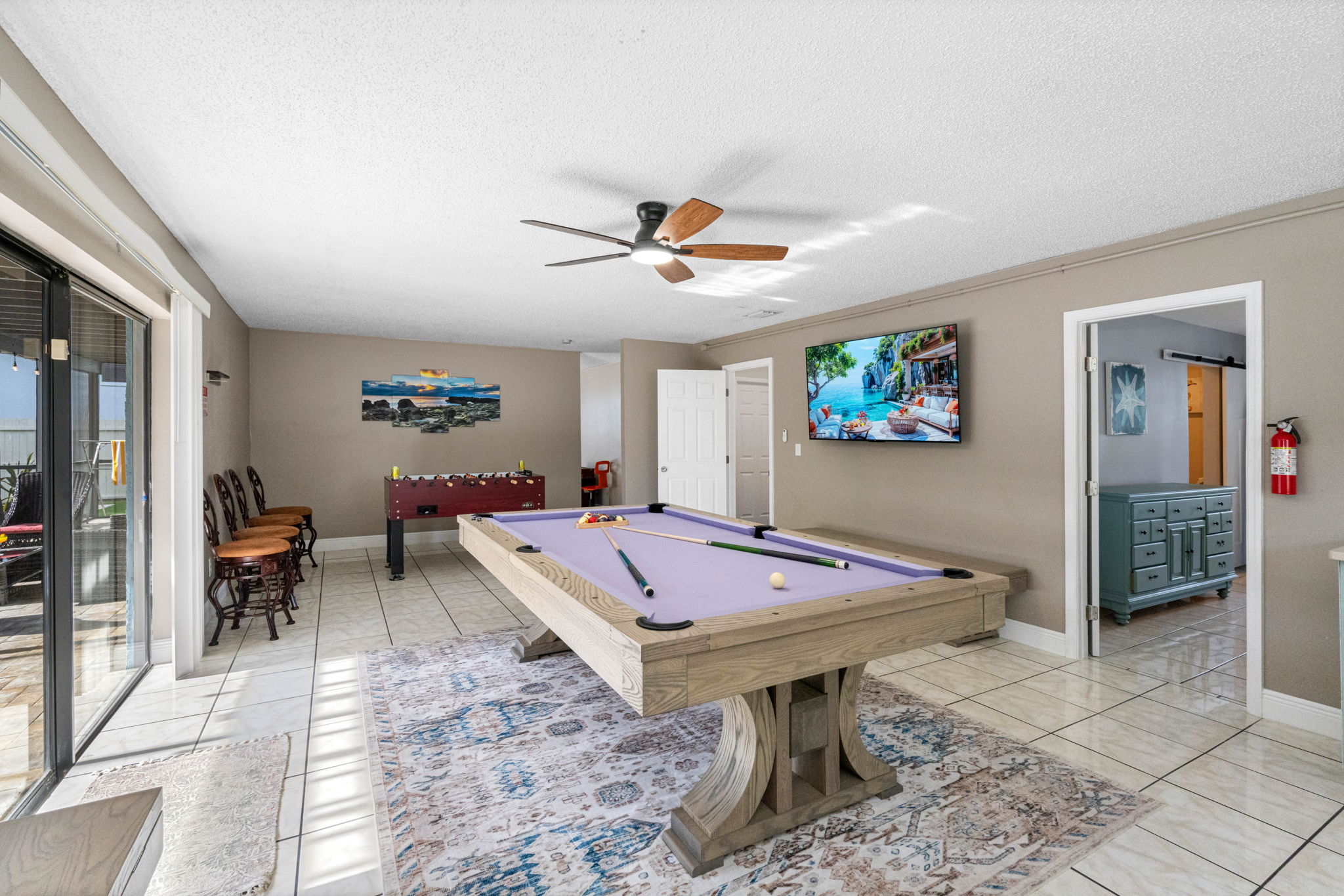 The room is thoughtfully designed with soft neutral tones, tile flooring for easy cleanup, and a ceiling fan to keep you cool while the action heats up.